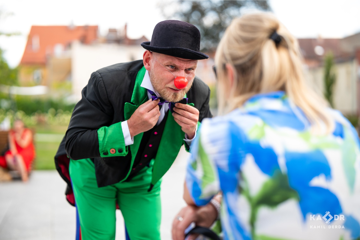 Klown w meloniku kłania się pani na placu teatralnym