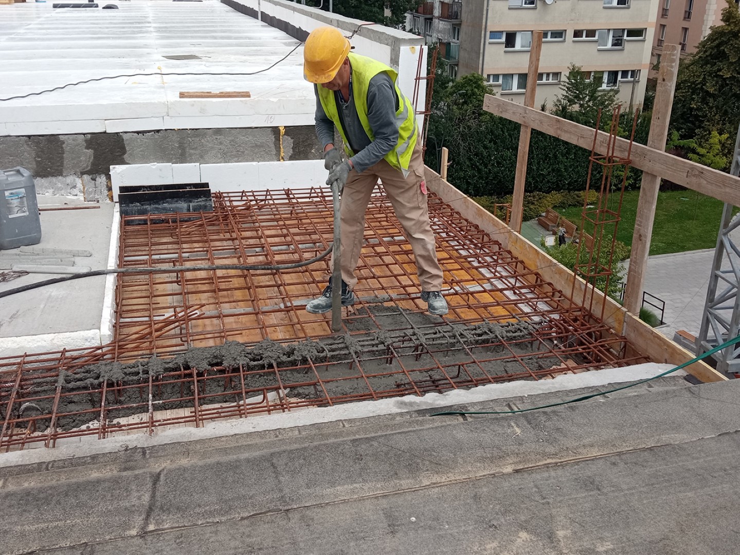 Wylewanie żel-betonu na dachu przez pracownika budowlanego.